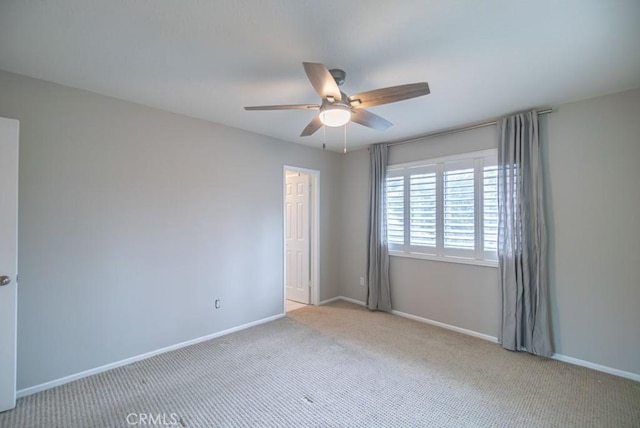 carpeted spare room featuring baseboards and ceiling fan