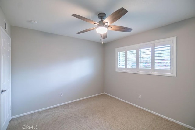 empty room with light colored carpet, baseboards, and ceiling fan