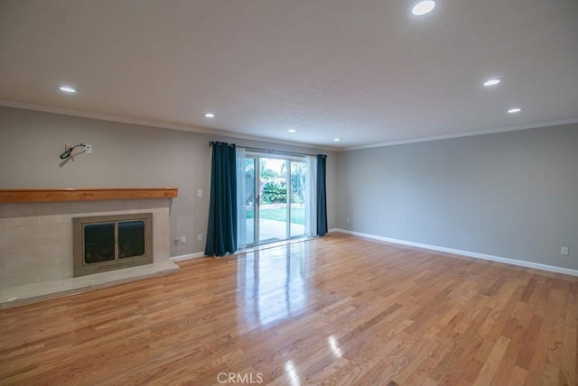 unfurnished living room with wood finished floors, a fireplace, baseboards, and ornamental molding