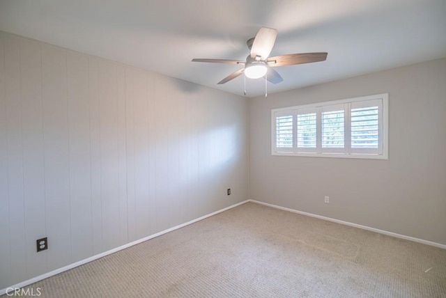 empty room featuring baseboards, a ceiling fan, and carpet