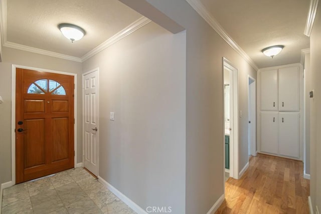 foyer entrance with light wood finished floors, a textured ceiling, crown molding, and baseboards