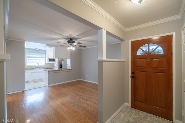 foyer with baseboards, light wood-style floors, ceiling fan, and crown molding