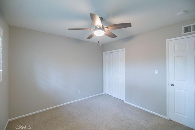 unfurnished bedroom featuring visible vents, baseboards, carpet floors, a closet, and a ceiling fan