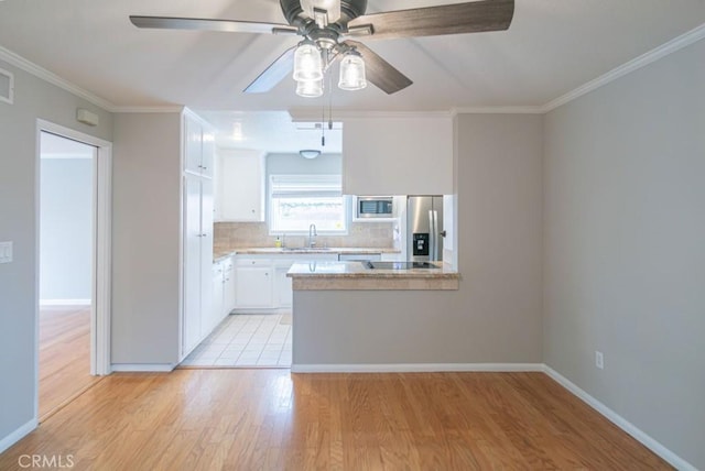 kitchen with ornamental molding, appliances with stainless steel finishes, light wood-style floors, white cabinetry, and a sink