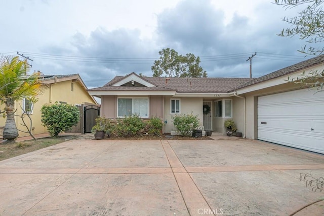 ranch-style house with concrete driveway, a gate, a garage, and stucco siding