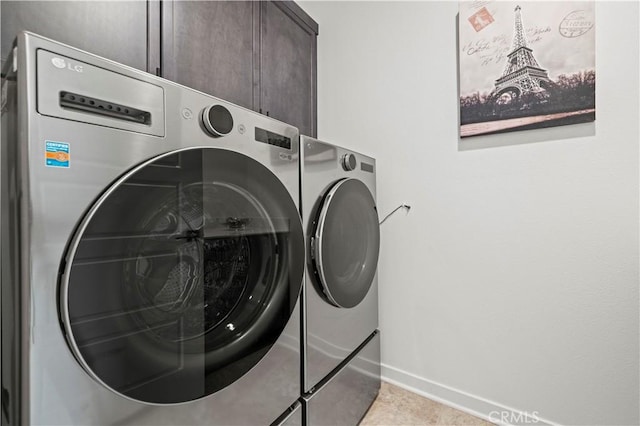 clothes washing area featuring tile patterned floors, cabinet space, baseboards, and washer and clothes dryer