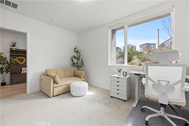 office area featuring visible vents, light colored carpet, and baseboards