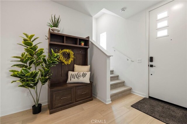 entrance foyer with baseboards, light wood finished floors, and stairs