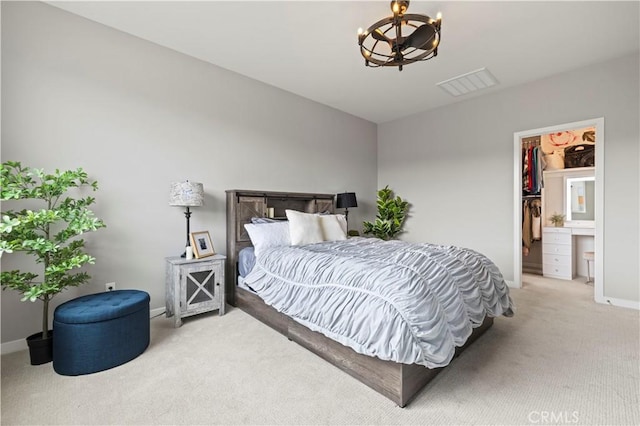 bedroom with visible vents, a walk in closet, baseboards, light colored carpet, and a notable chandelier