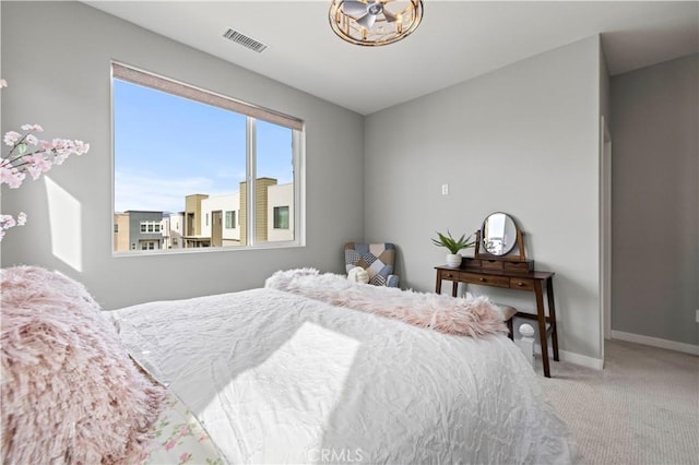 carpeted bedroom featuring a chandelier, baseboards, and visible vents