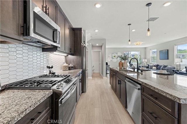 kitchen with appliances with stainless steel finishes, a sink, and dark brown cabinetry