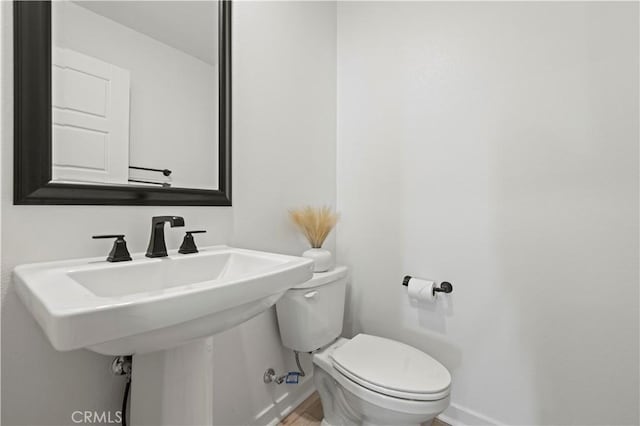 bathroom featuring baseboards, toilet, and wood finished floors
