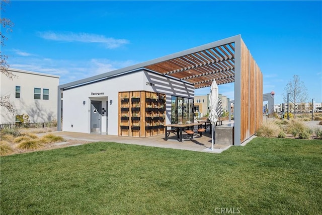 back of house with stucco siding, a patio, a pergola, and a yard