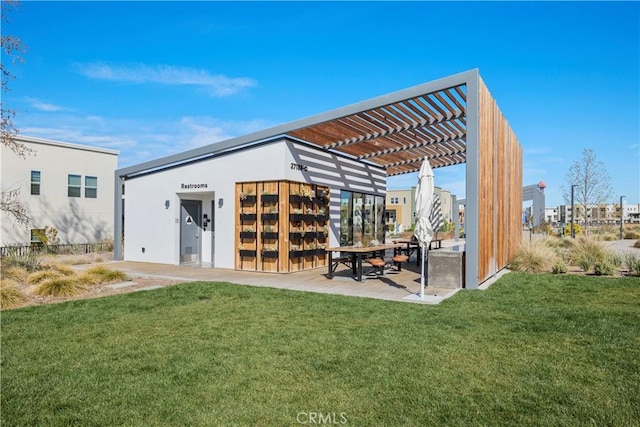 back of property with a pergola, a patio, stucco siding, and a lawn