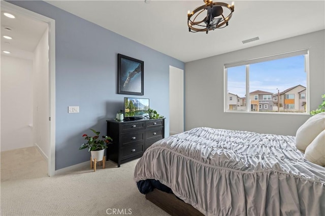 bedroom featuring light colored carpet, visible vents, a chandelier, and baseboards