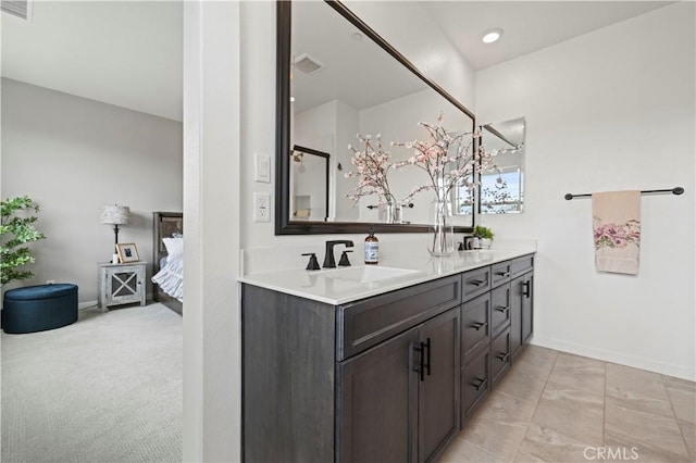 ensuite bathroom with visible vents, a sink, ensuite bath, double vanity, and baseboards