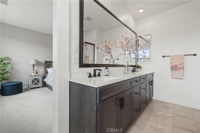ensuite bathroom featuring connected bathroom, visible vents, a sink, double vanity, and baseboards
