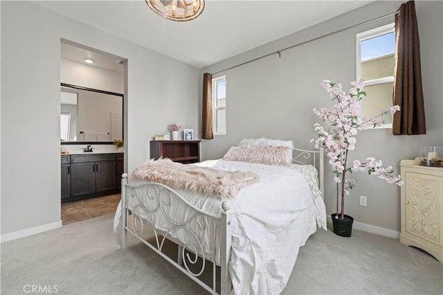 bedroom with a sink, baseboards, connected bathroom, and light colored carpet