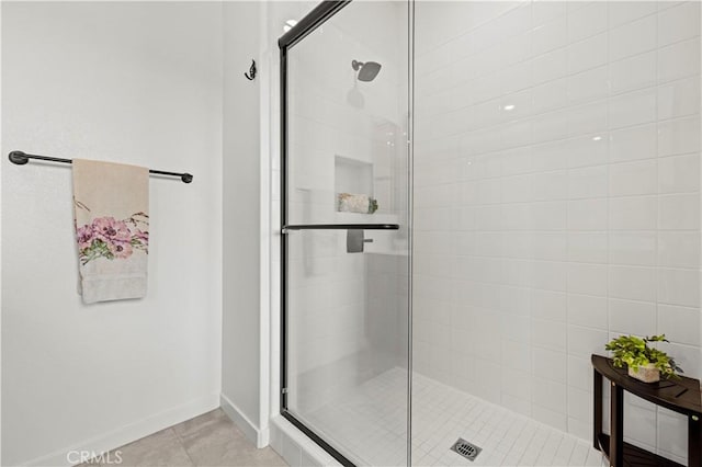 full bath featuring tile patterned flooring, a shower stall, and baseboards