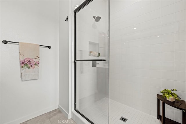 bathroom with a shower stall, tile patterned flooring, and baseboards