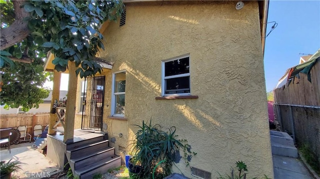 view of property exterior with a patio, fence, and stucco siding