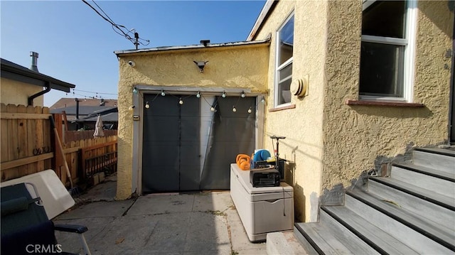 exterior space featuring fence, a garage, and stucco siding