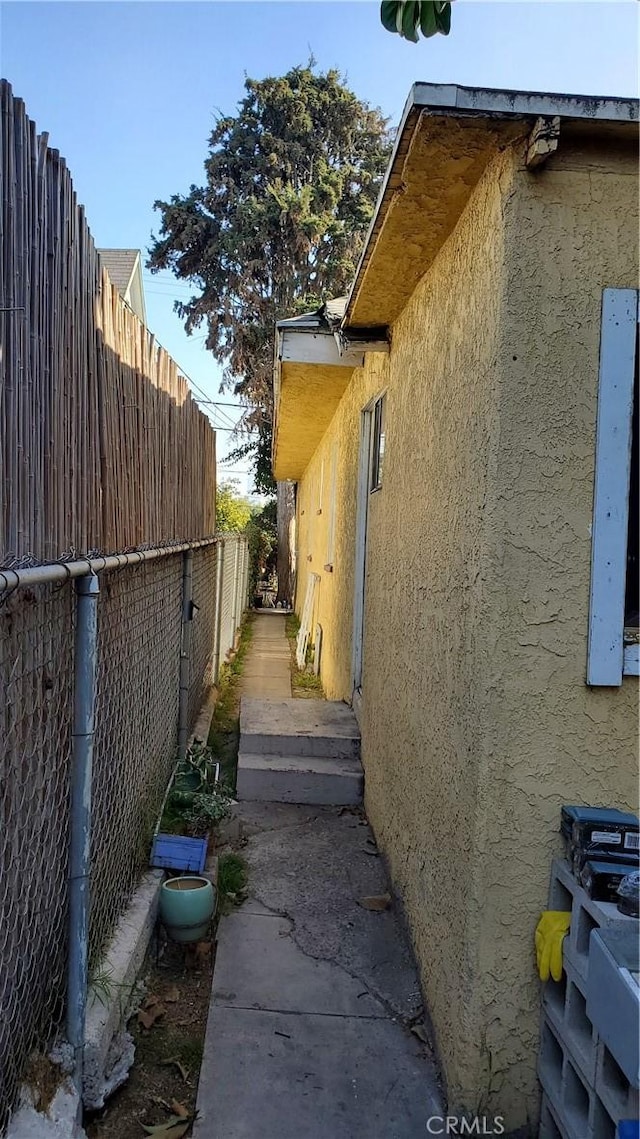 view of property exterior with stucco siding and fence