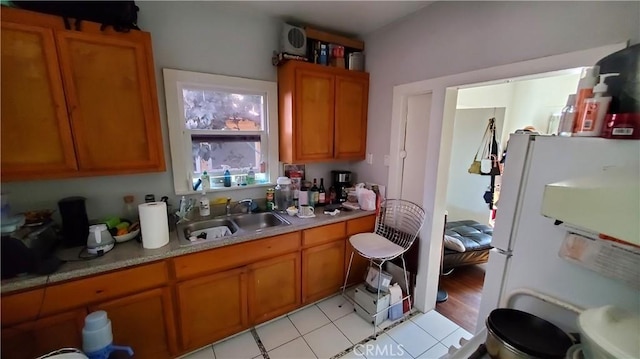 kitchen with brown cabinets, light countertops, freestanding refrigerator, and a sink