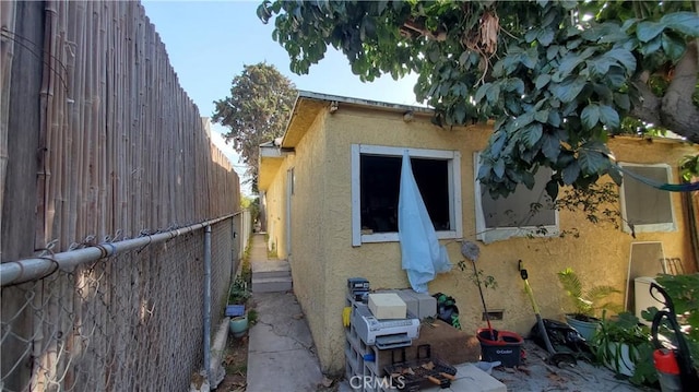 view of property exterior with stucco siding and fence