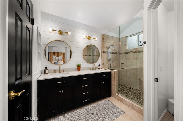 full bathroom with a sink, double vanity, a shower stall, and tile patterned flooring