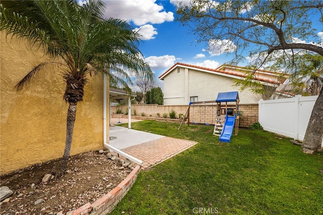 view of yard with a patio area, a playground, and a fenced backyard