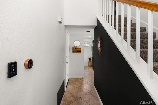 hall featuring tile patterned floors, visible vents, baseboards, and stairs