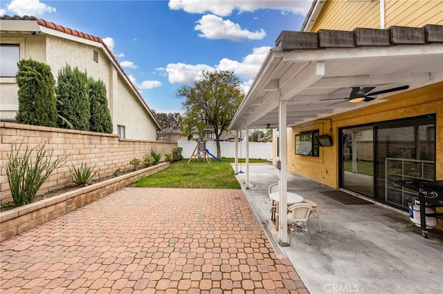 view of patio / terrace featuring a fenced backyard, a playground, and ceiling fan