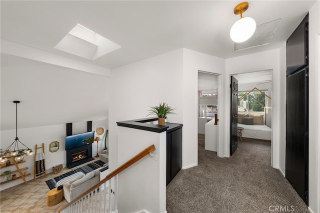 hall with an upstairs landing, carpet, and a skylight