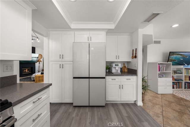 kitchen with visible vents, white cabinets, freestanding refrigerator, and a tray ceiling