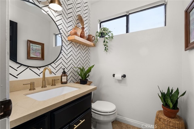 half bathroom featuring toilet, vanity, and baseboards