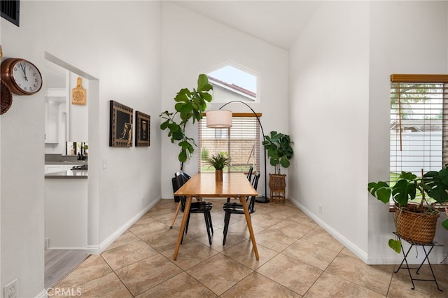 dining room with light tile patterned floors, visible vents, high vaulted ceiling, and baseboards