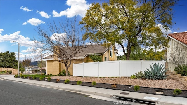 view of side of home featuring a tiled roof and fence