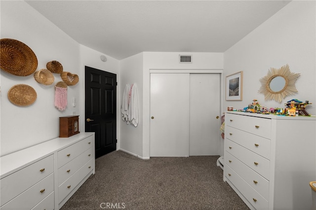 bedroom featuring dark colored carpet, visible vents, and a closet