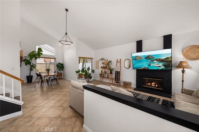 living room with light tile patterned floors, a brick fireplace, high vaulted ceiling, and an inviting chandelier