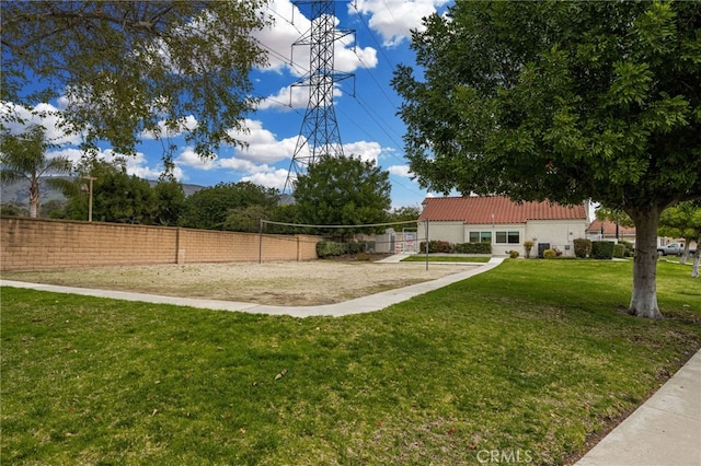 view of home's community with volleyball court, a yard, and fence