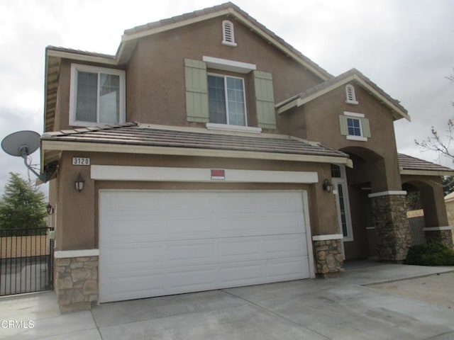 view of front of home with stucco siding, stone siding, a garage, and concrete driveway