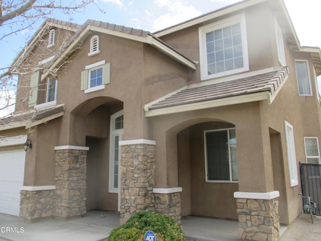 view of front of property featuring a porch, stone siding, stucco siding, and a tiled roof