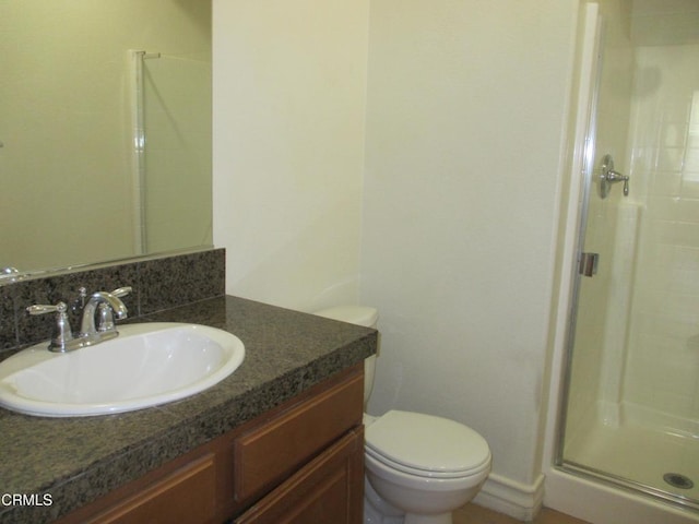 bathroom featuring toilet, a stall shower, and vanity