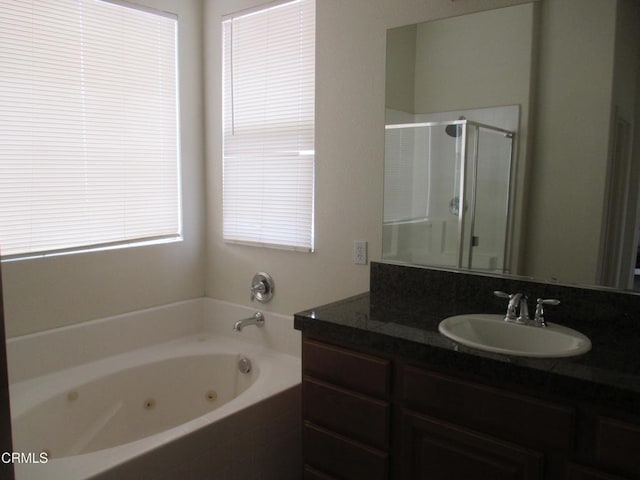 full bath with a stall shower, vanity, and a whirlpool tub