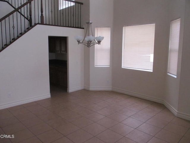 unfurnished living room with plenty of natural light, baseboards, and an inviting chandelier