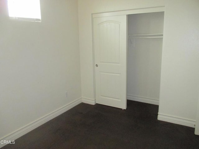 unfurnished bedroom with a closet and baseboards