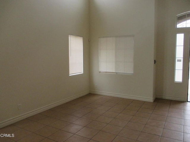 entrance foyer with light tile patterned floors, baseboards, and a towering ceiling