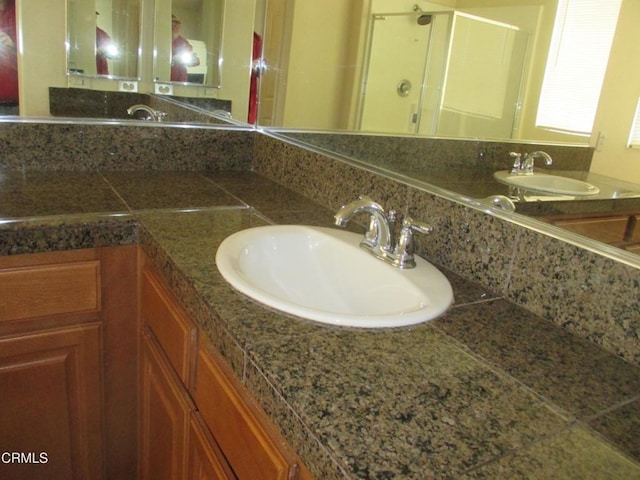 full bathroom with a sink, double vanity, and a shower stall