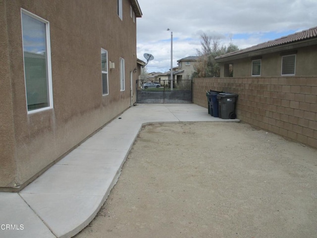 view of side of property with stucco siding, a patio, and fence